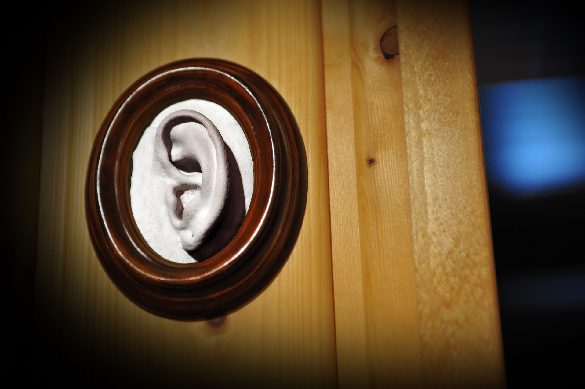 Eingerahmte Plastik eines Ohres hängt an einer Wand.