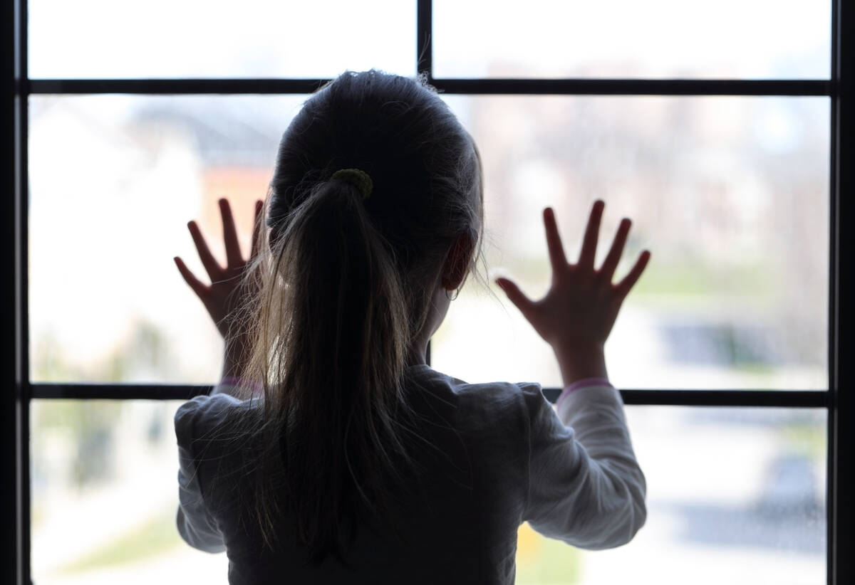 Kind am Fenster Kind im Schatten blickt aus dem hellen Fenster