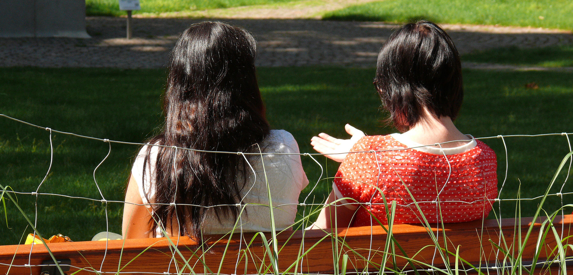 Zwei Frauen unterhalten sich auf einer Parkbank.